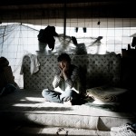 Greece, Patras. 16 year old Hababullah sits on his bed in an abandoned building where he squats.