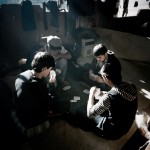 Greece, Patras. Young Afghan refugees play cards in an abandoned building where they squat.