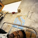 Italy, Palermo, Sicily. Birex (23), an Ethiopian, sleeps underneath a map of Italy at the immigration reception centre. Thousands of would-be asylum seekers have made the perilous crossing from North Africa to the southern stretch of Sicilian coastline.