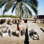 
A man exercises in front of his house while two friends clean fish for their lunch.